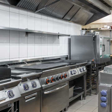 Restaurant kitchen featuring stainless steel appliances such as a grill, convection oven, and flat-top