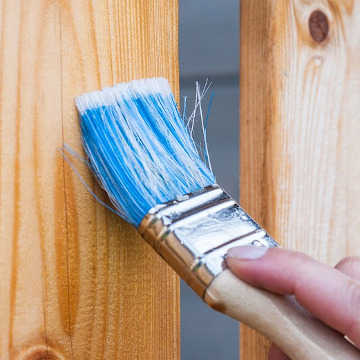 Wooden post being painted using paint brush