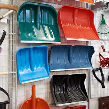 Several different types of snow shovels hanging on a rack in a store