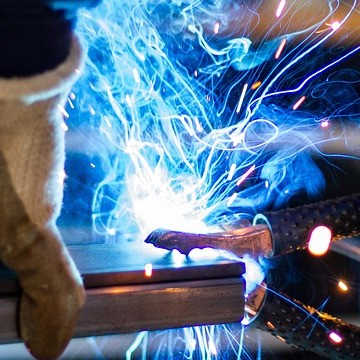 The hands of a person in protective equipment as they are welding